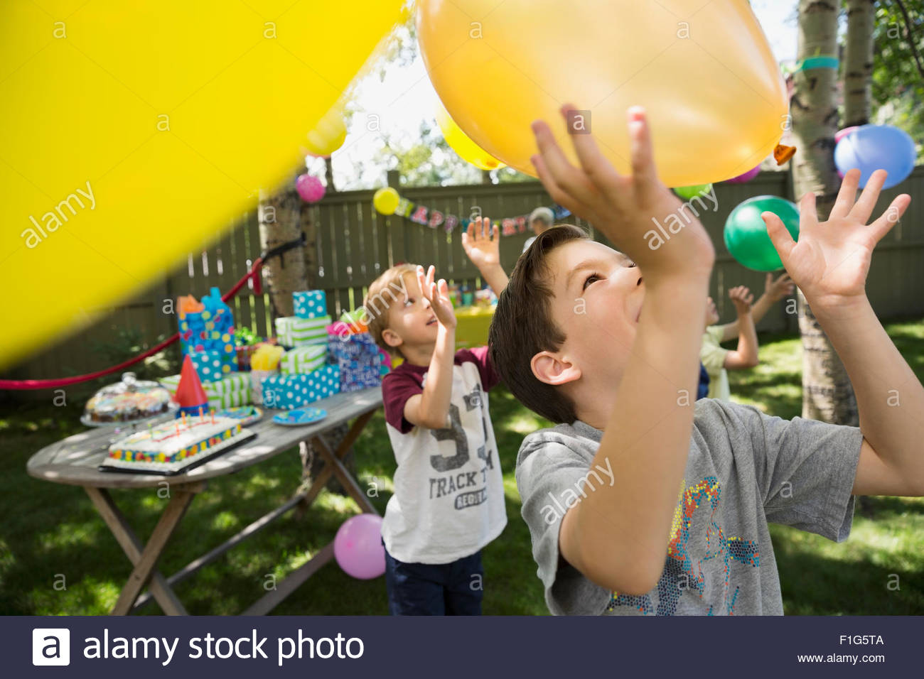 Muchachos jugando con globos en la fiesta de cumpleaños de traspatio Foto de stock