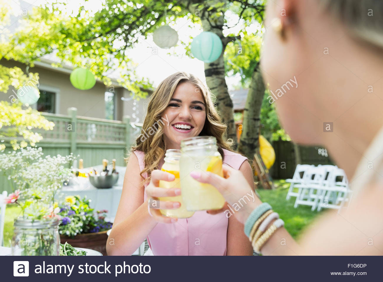 Mujer sonriente tostado jarras de limonada en garden party Foto de stock