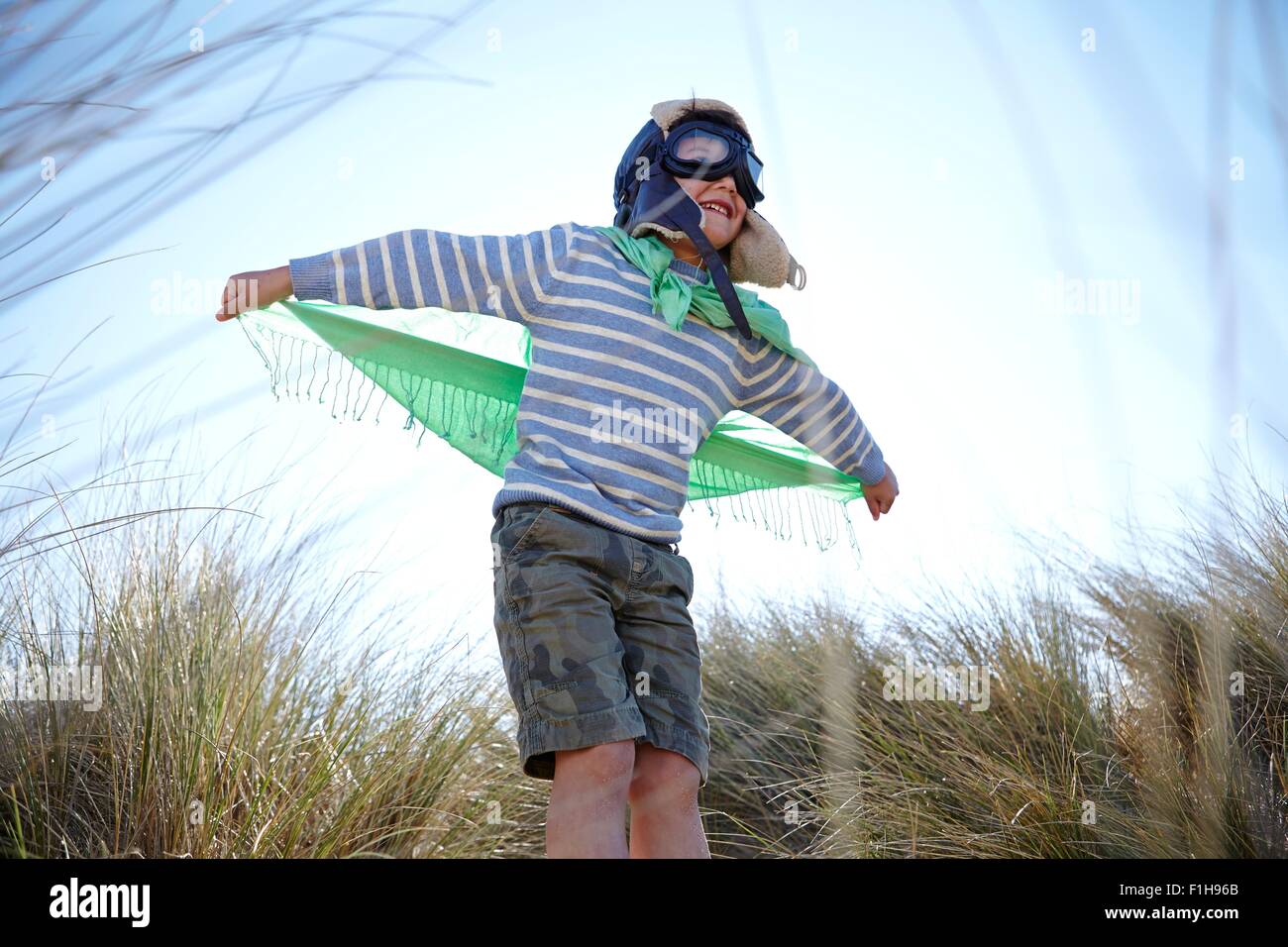 Joven en la playa, vistiendo disfraces, pretendiendo volar Foto de stock
