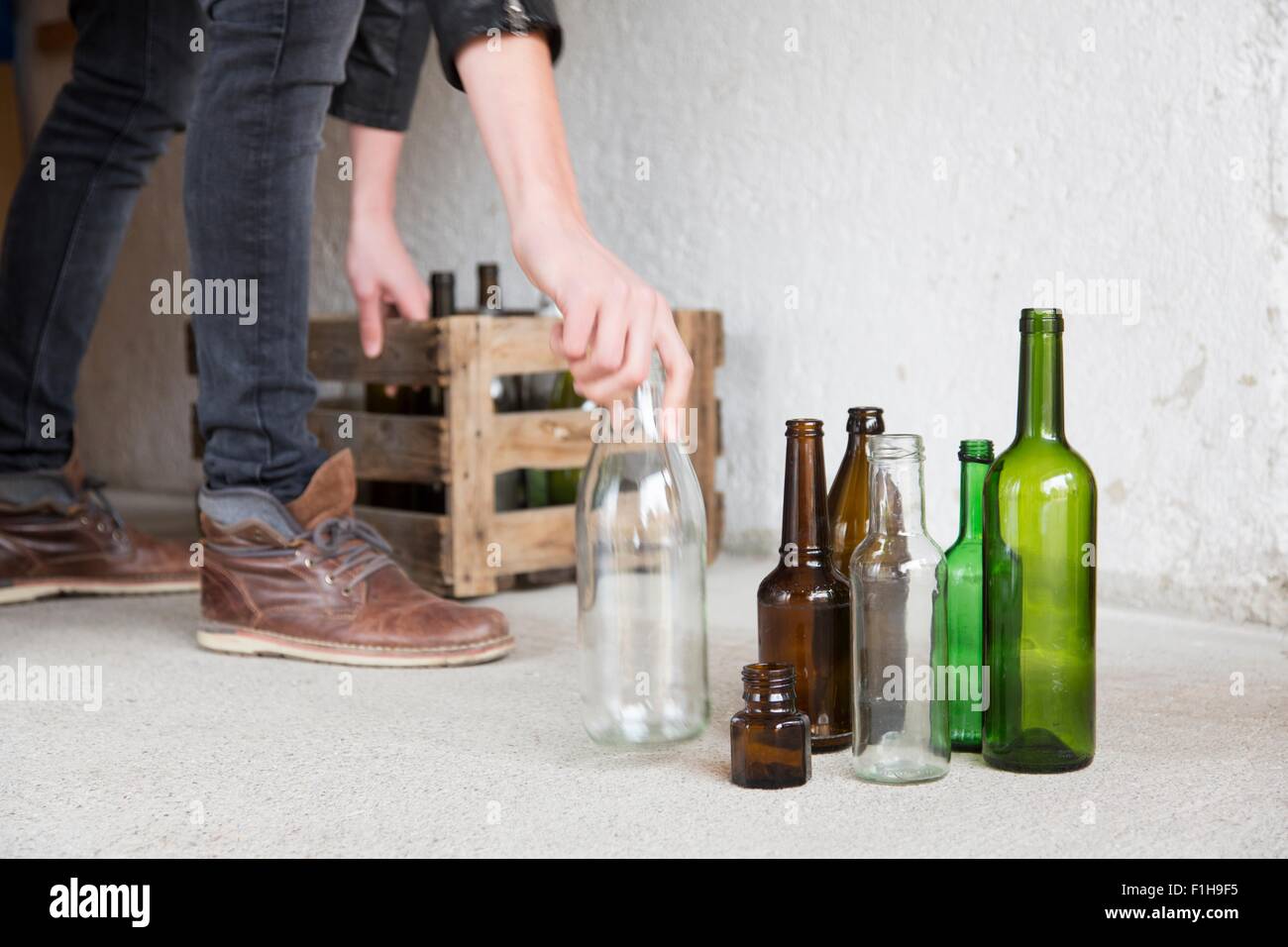 Adolescente colocando las botellas vacías en jaula de madera en el garaje Foto de stock