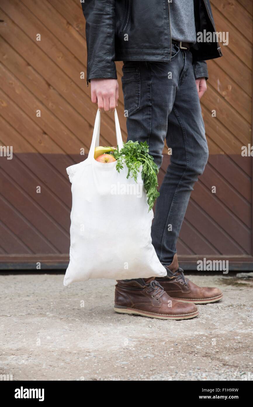 Adolescente llevando bolsas reutilizables lleno de frutas y verduras Foto de stock