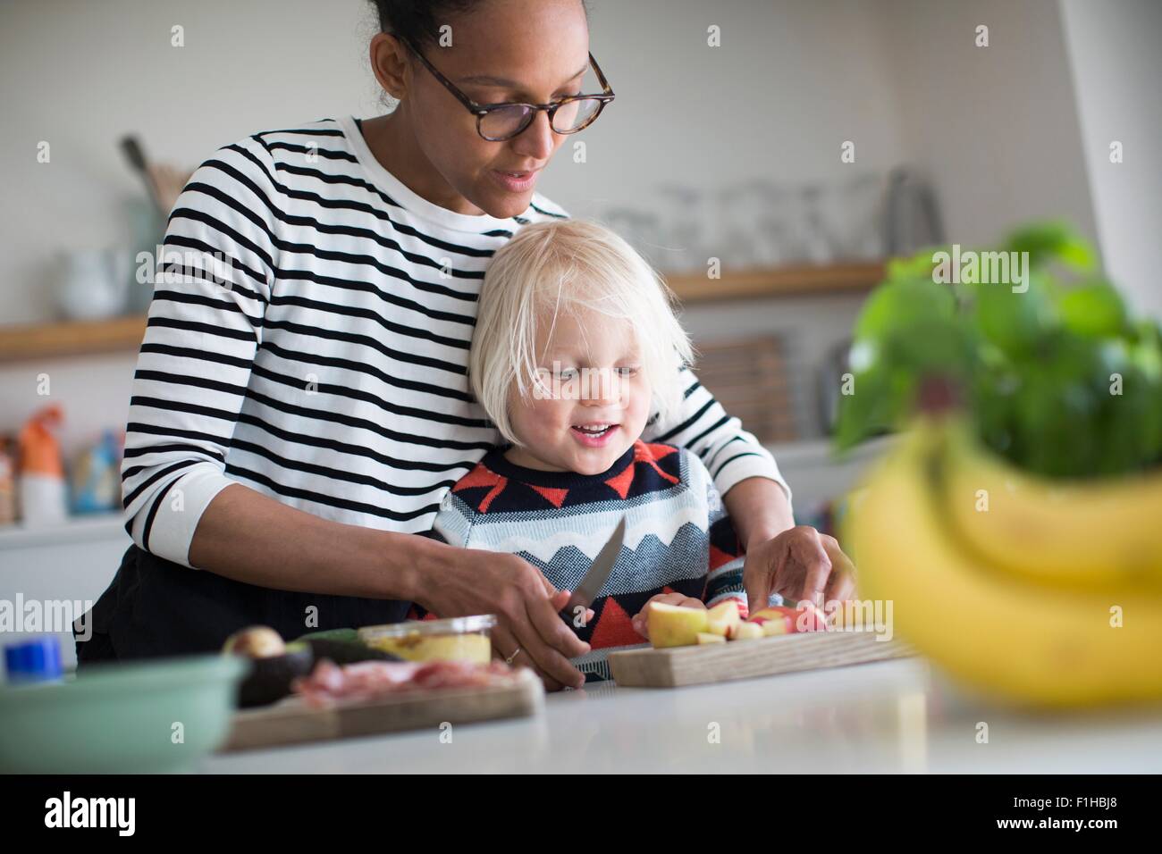Ayudar a la madre a preparar la comida en la cocina de sone Foto de stock