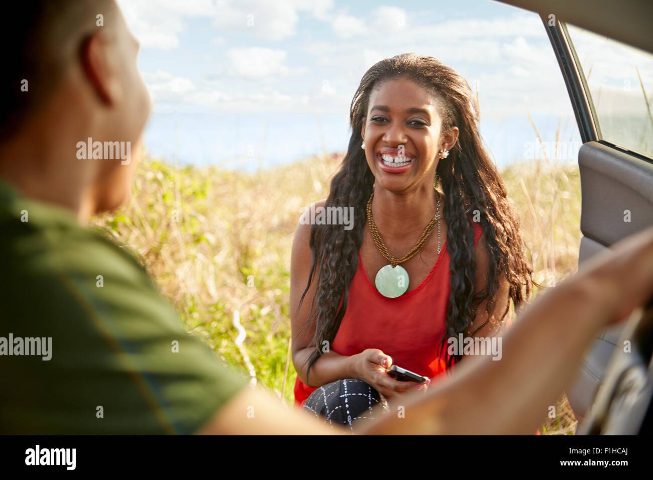 Mujer joven de abrir puertas de coches smartphone holding sonriendo Foto de stock