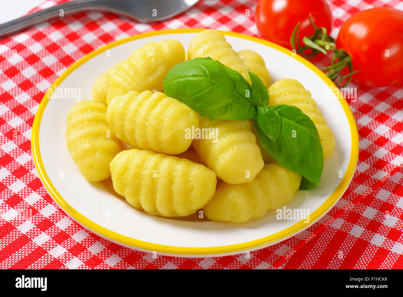 Plato de ñoquis cocidos sobre manteles a cuadros Foto de stock