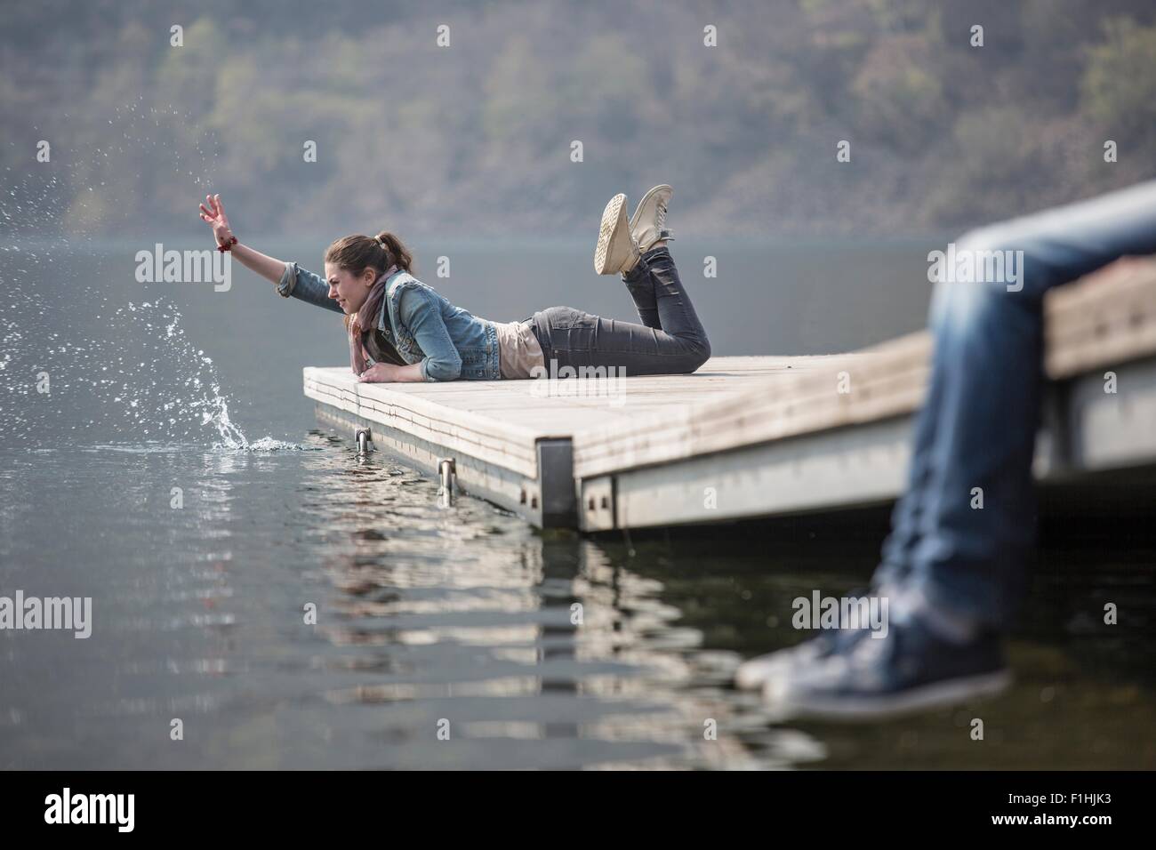 Mujer joven acostado en el muelle salpicaduras en el lago de Mergozzo, Verbania, Piemonte, Italia Foto de stock