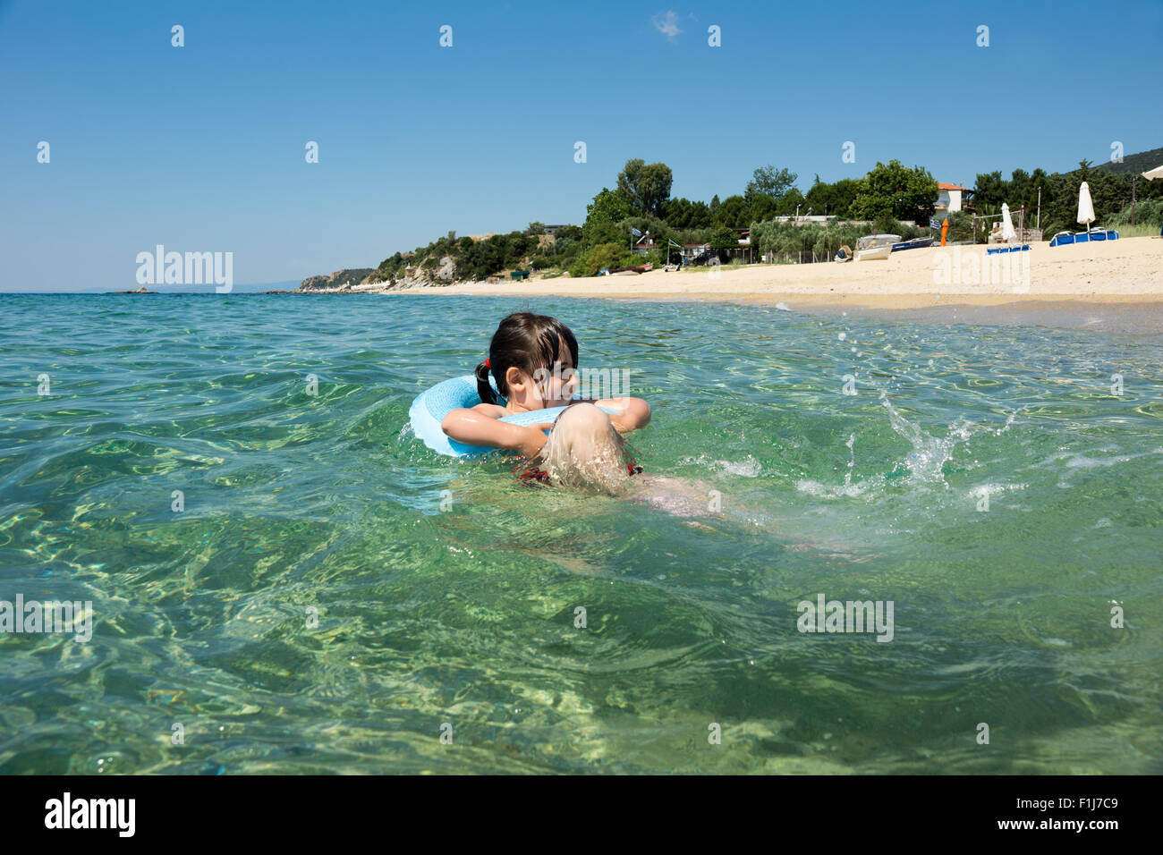 Niño con anillo flotante divirtiéndose en el mar Foto de stock