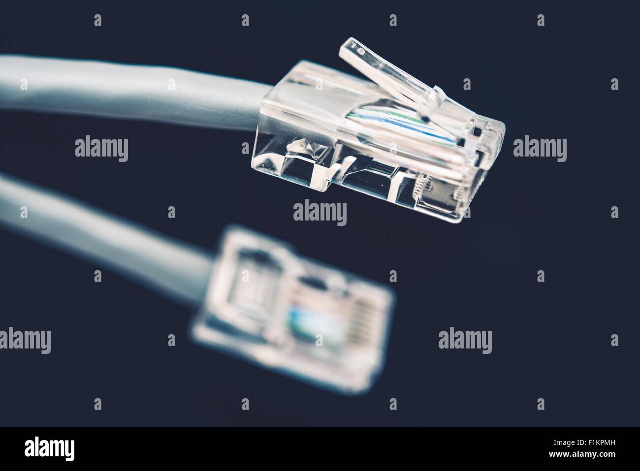 Cable de red gris de cable con conector RJ45 en el fondo azul oscuro Foto de stock