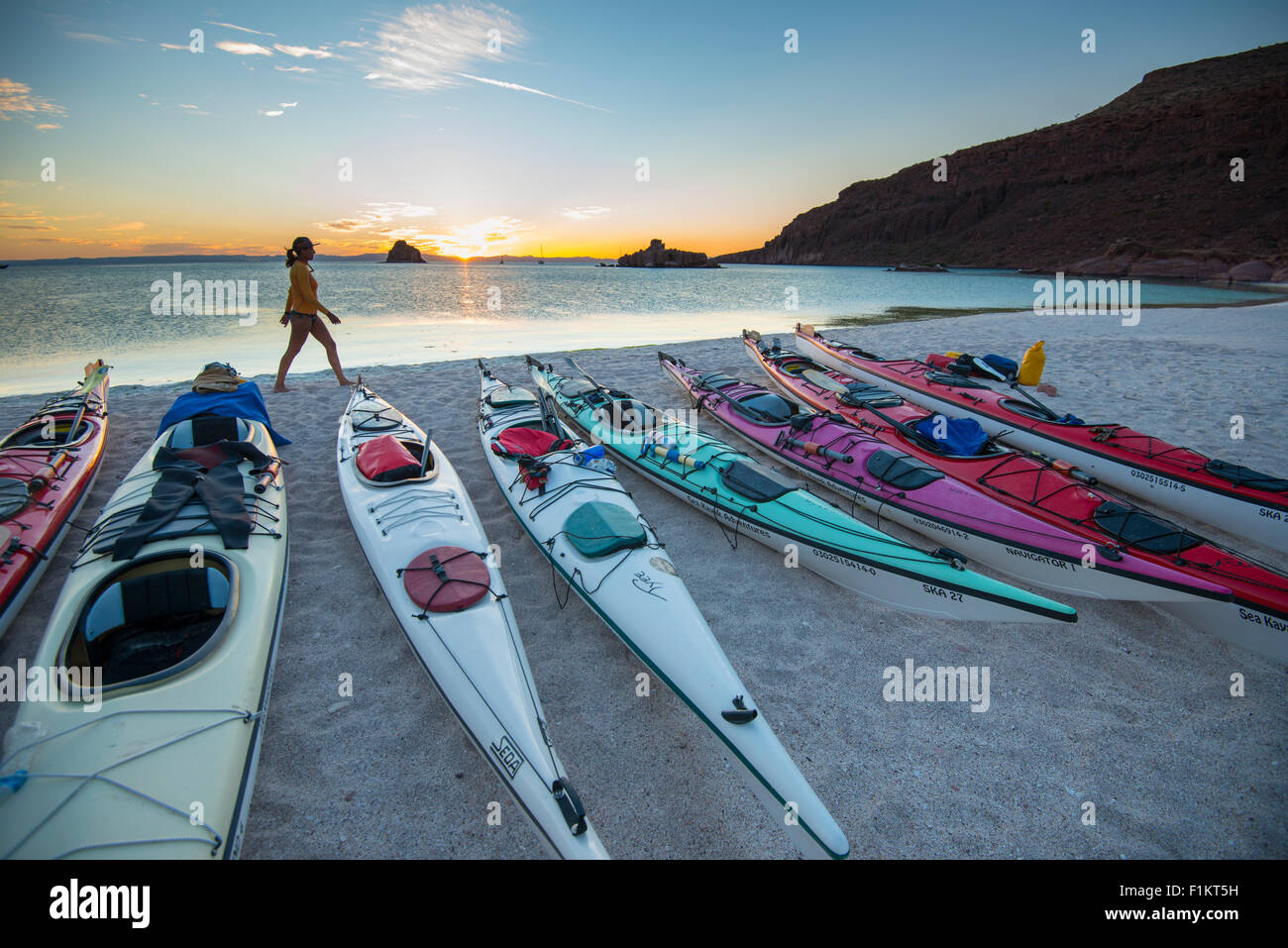México, Baja, Lapaz, Espiritu Santo. Mujer de pie cerca de los kayaks durante la puesta de sol. Foto de stock