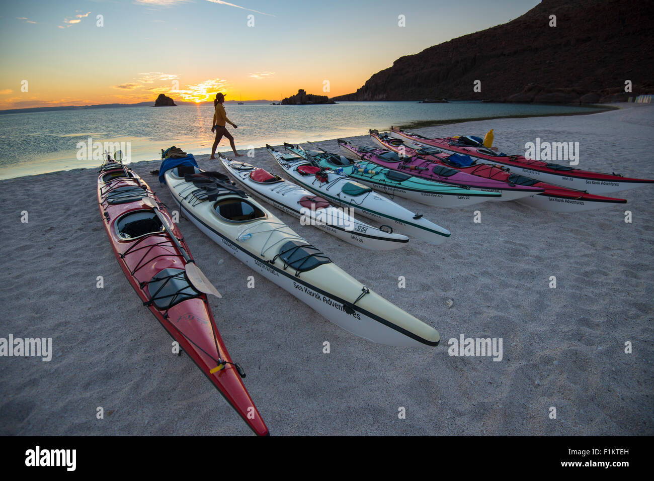 México, Baja, Lapaz, Espiritu Santo. Mujer de pie cerca de los kayaks durante la puesta de sol. Foto de stock