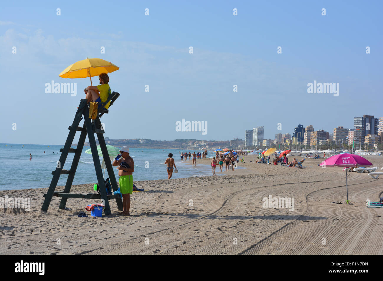 Mirando hacia la ciudad de Alicante desde la playa de El Campello con un socorrista. Temprano en la mañana a finales de agosto. Foto de stock