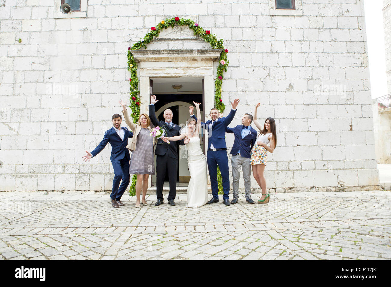 Pareja casada y los invitados a la boda vítores delante de la capilla de bodas Foto de stock