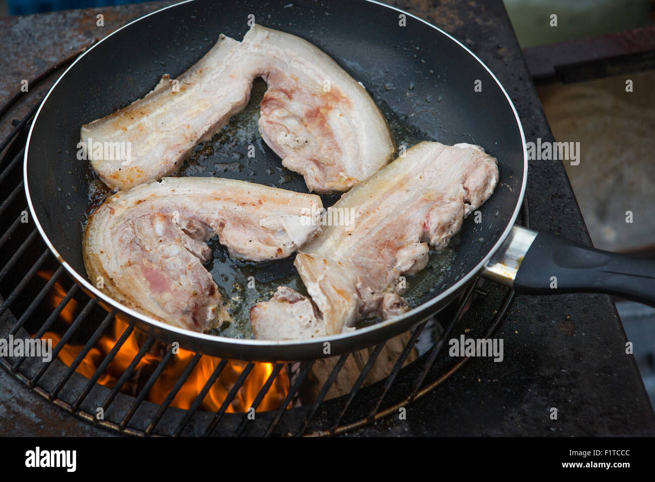 Ecológico y sostenible crecido bacon está frito sobre una estufa de leña en aventuras al aire libre Foto de stock