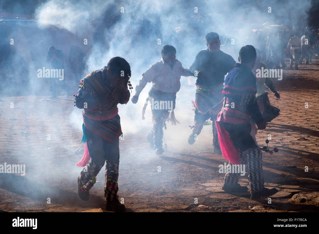 Varios asistentes a la celebración del Tinku corren entre el gas lacrimógeno que ha sumido a la policía para evitar peleas en el grupo Foto de stock