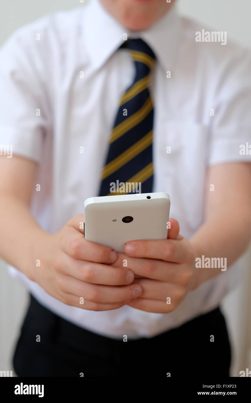 Un niño en uniforme utilizando su teléfono móvil ( Texto ) UK Foto de stock