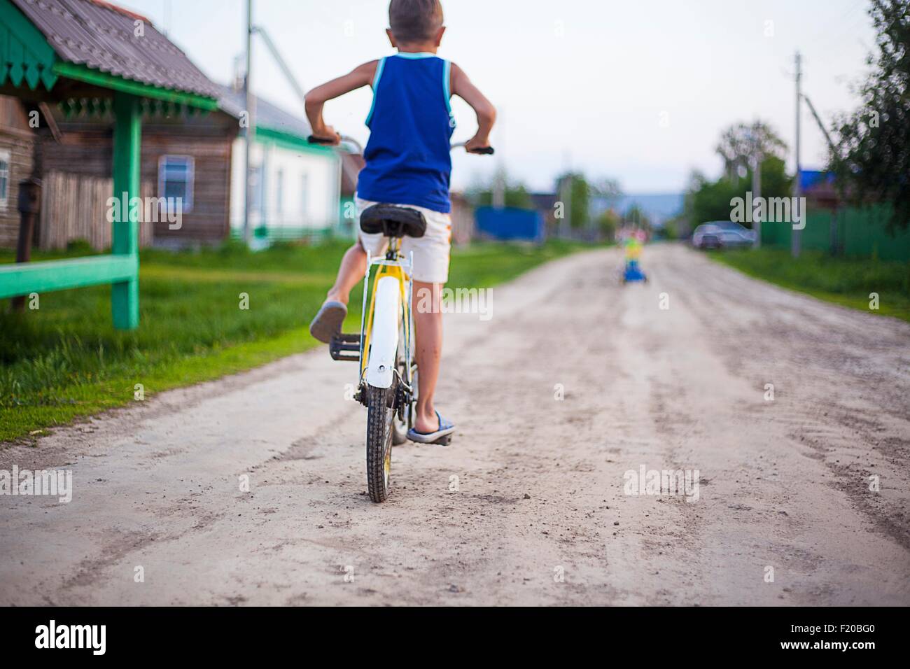 Joven, montando en bicicleta por camino de tierra, vista trasera Foto de stock