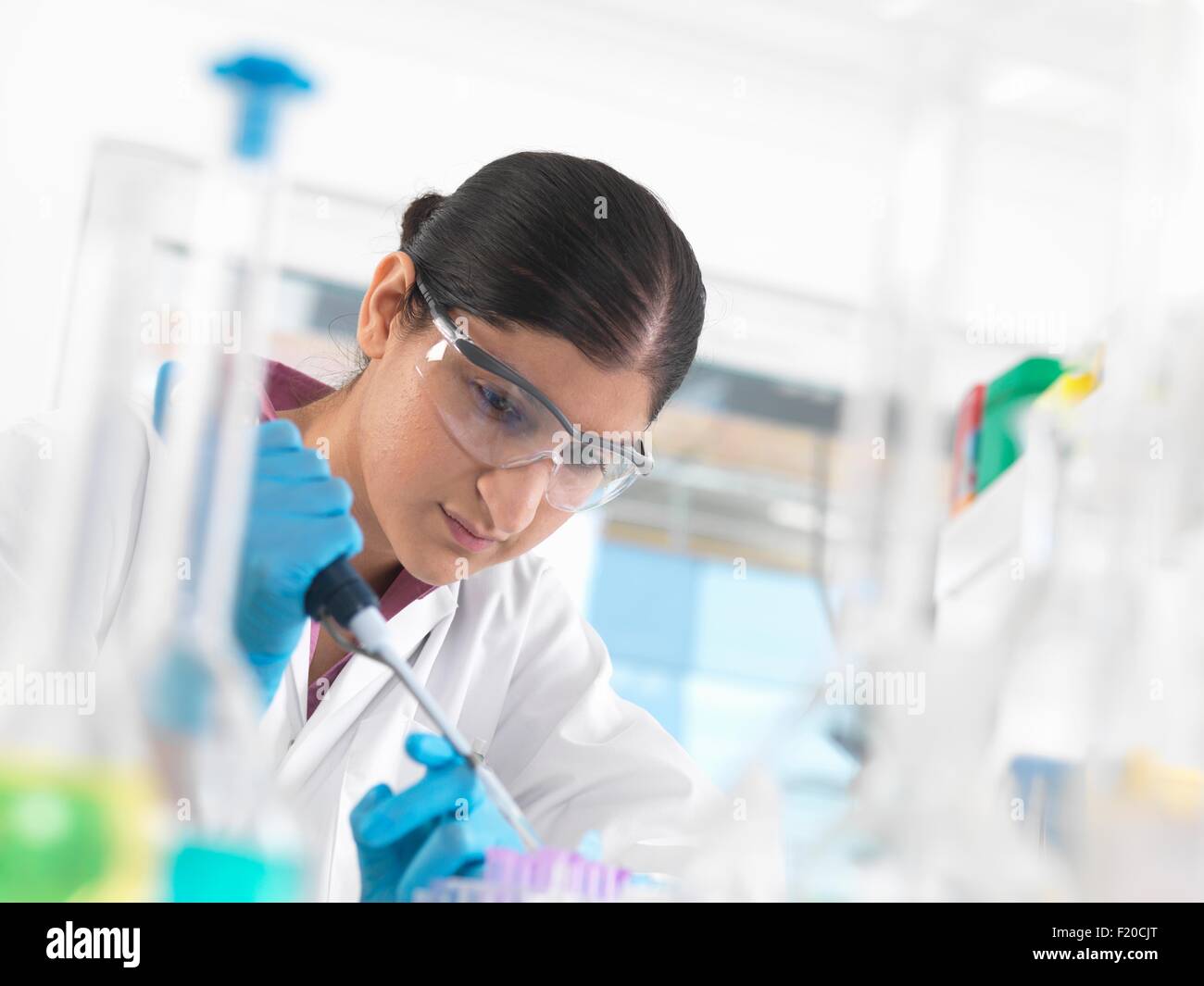 Joven Científico el pipeteo de muestra en frasco en un laboratorio utilizado para productos químicos y las pruebas de ADN Foto de stock
