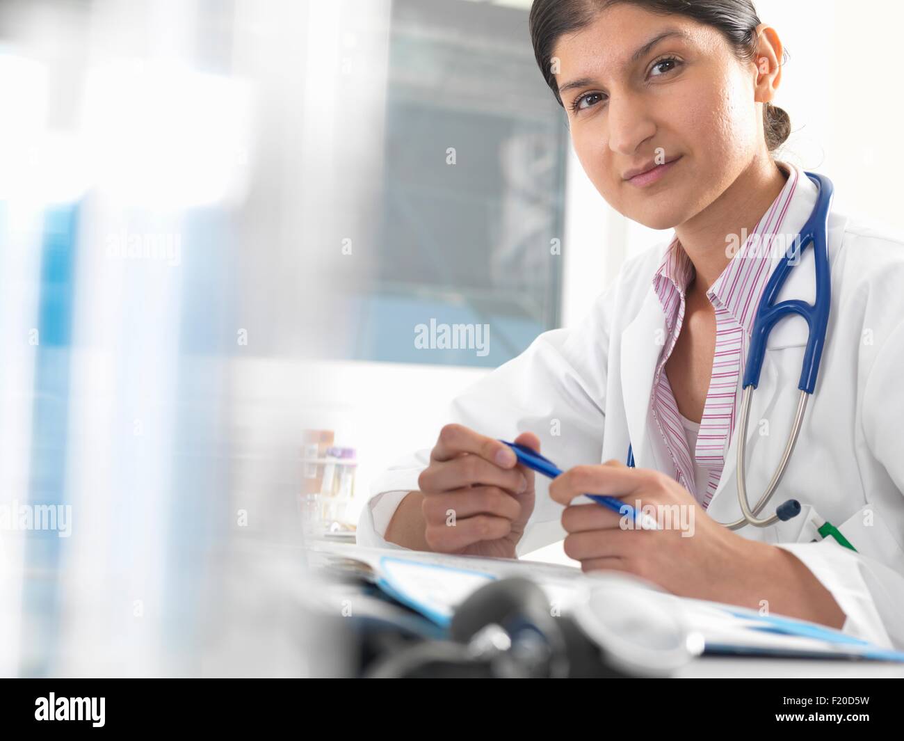 Retrato de mujer doctor en la mesa de trabajo sobre registros médicos Foto de stock