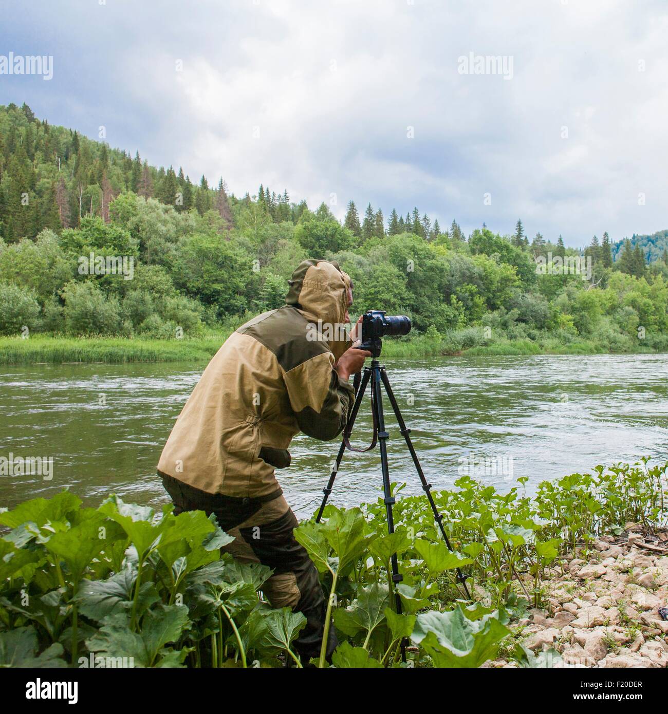 Fotógrafo macho fotografiando río rural Foto de stock
