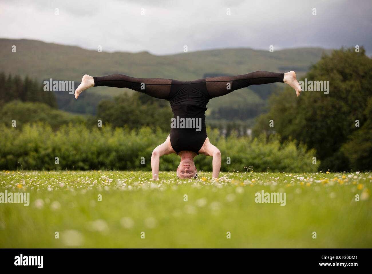 Mujer madura practicando yoga de pie en cabeza con piernas abiertas en el  campo Fotografía de stock - Alamy