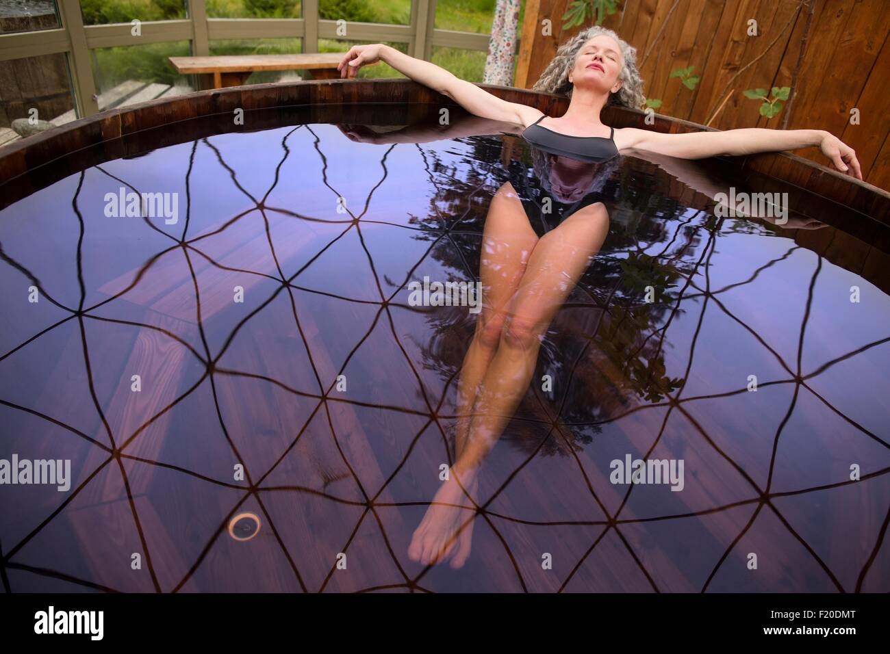 Mujer madura de tumbarse en la bañera caliente en eco retreat Foto de stock