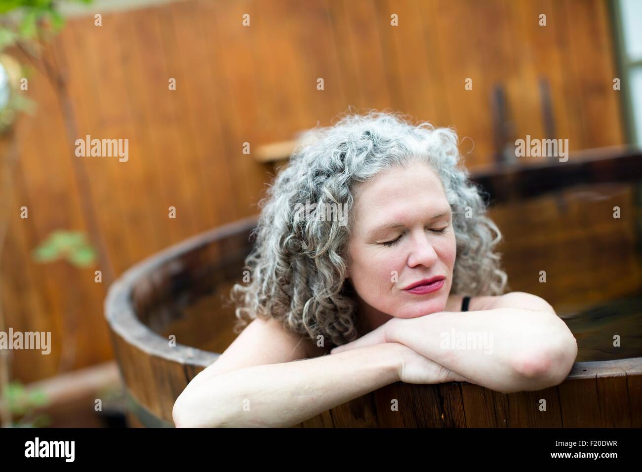 Mujer madura descansando en manos de ofuro en eco retreat Foto de stock
