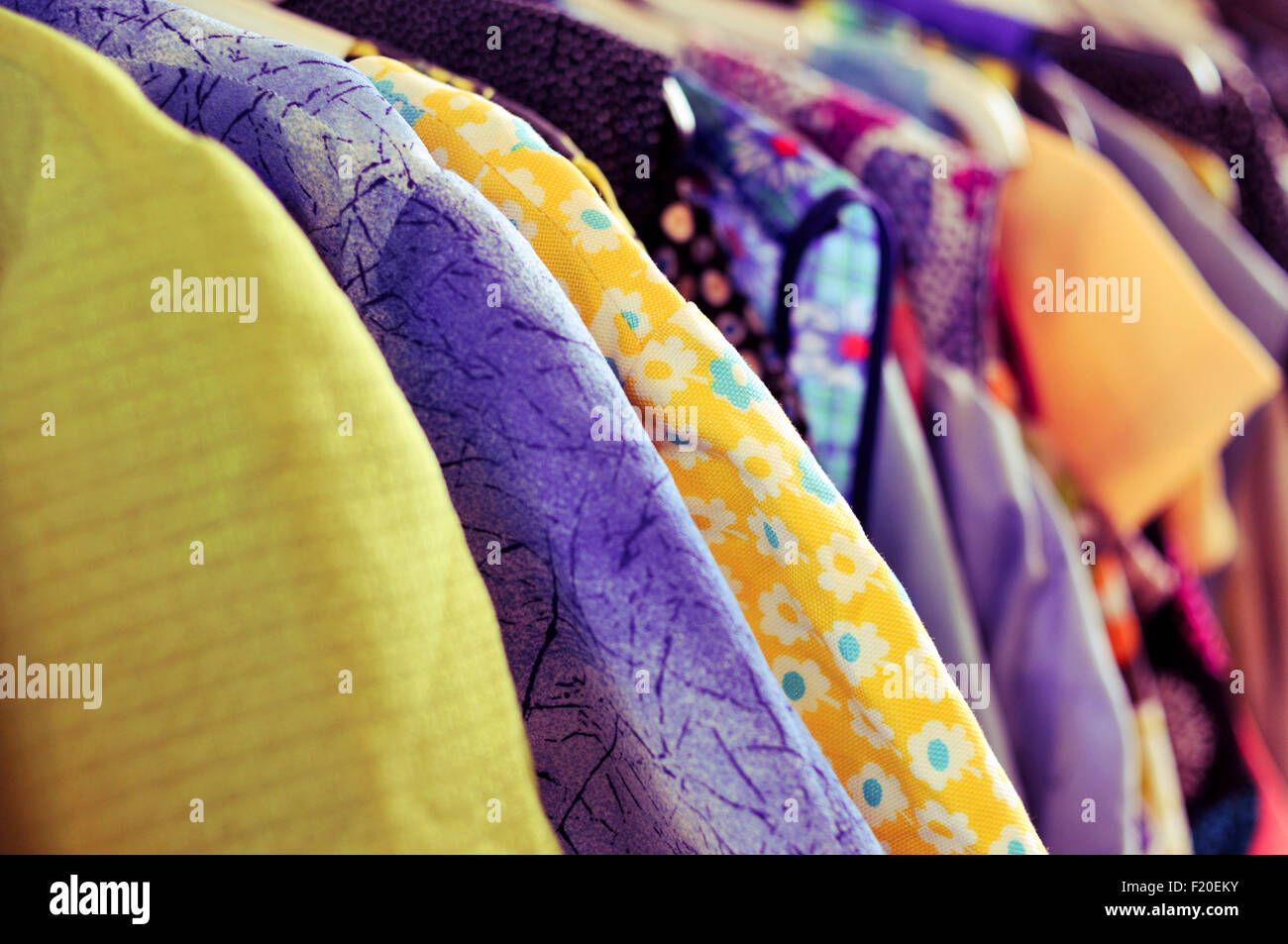 Algunos utilizan diferentes ropa colgando sobre un estante en un mercado de pulgas Foto de stock