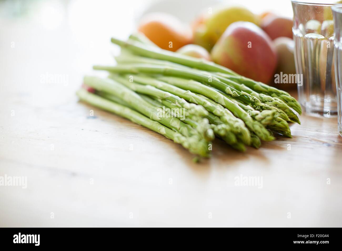 Espárragos, frutas, vaso para beber en la mesa de comedor Foto de stock