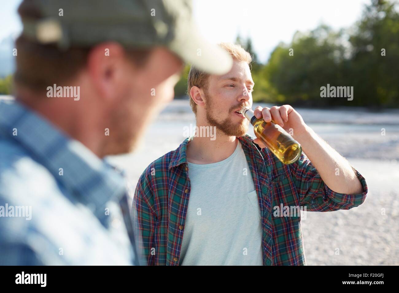 Joven tomando un trago de la botella de cerveza, mirando lejos Foto de stock
