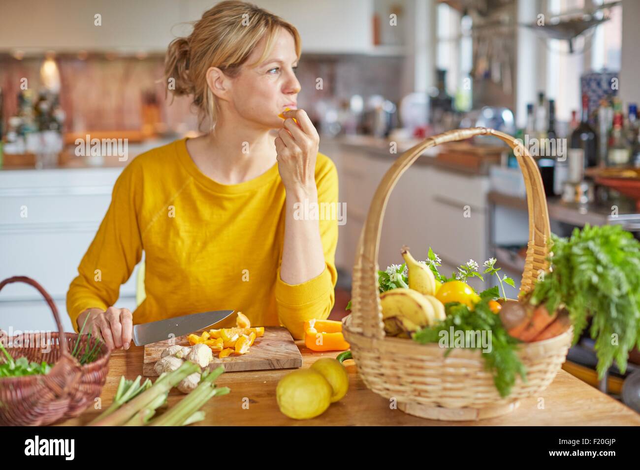 Mujer madura, sentado a la mesa de la cocina, picar las verduras Foto de stock