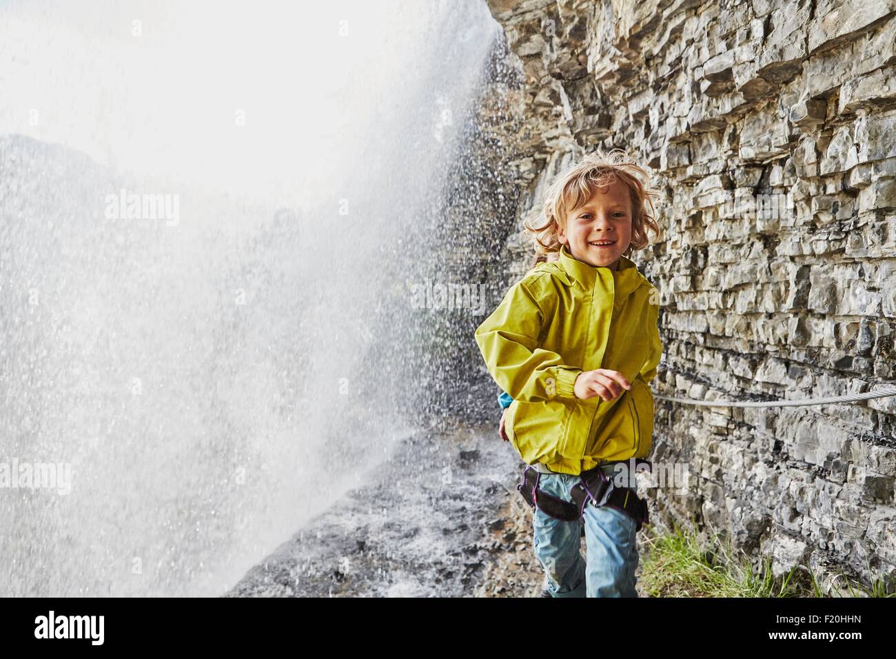 Muchacho caminando debajo de la cascada, sonriendo Foto de stock