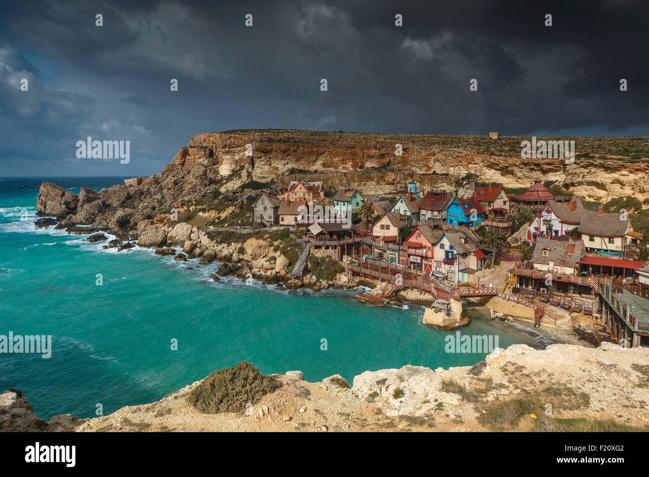 Malta, Mellieha, Anchor Bay, panorámica de la aldea de Popeye utilizado para el rodaje de una película, construido en la orilla del mar, bajo un cielo nublado Foto de stock