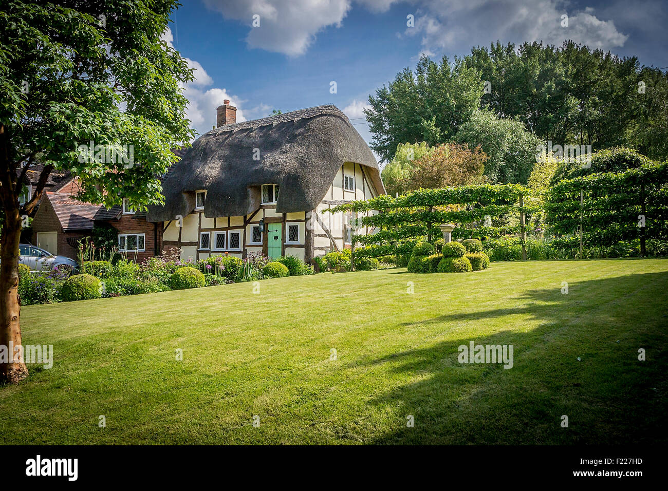Pintoresca casita con techo de paja y jardín inglés Foto de stock