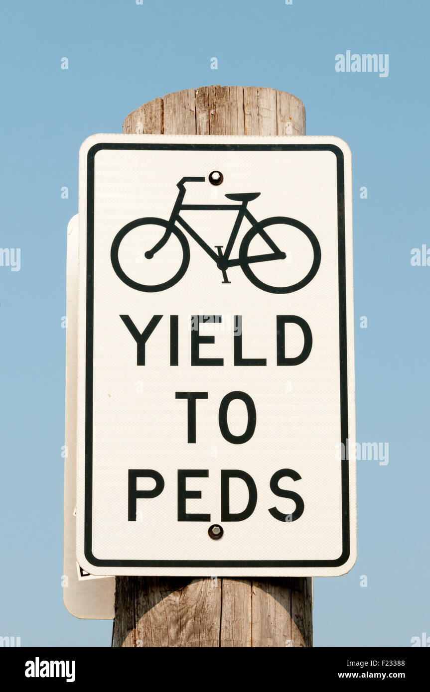 Un cartel indica a los ciclistas a ceder el paso a los peatones. Foto de stock
