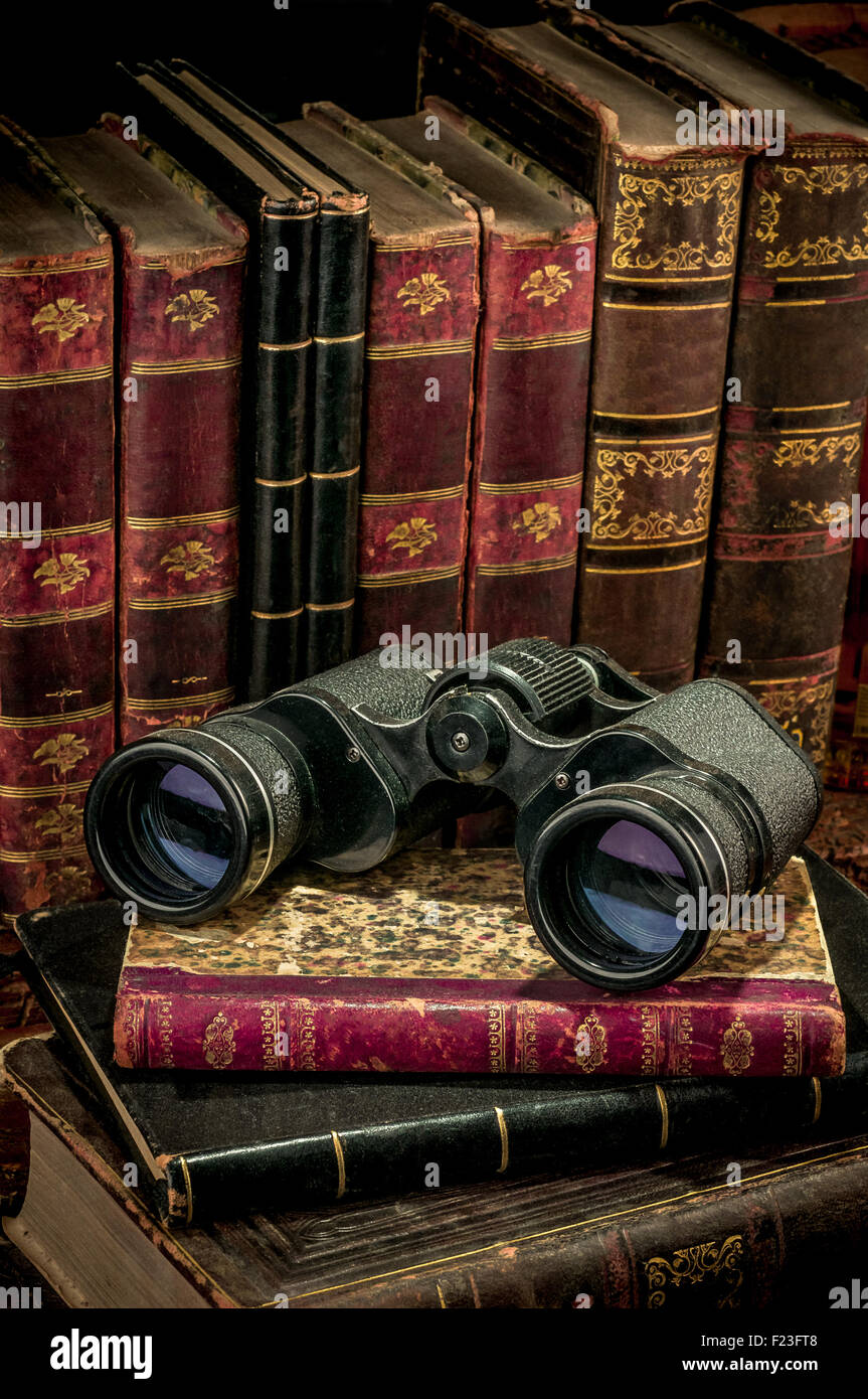 Los binoculares y libros antiguos sobre un mostrador de madera Foto de stock