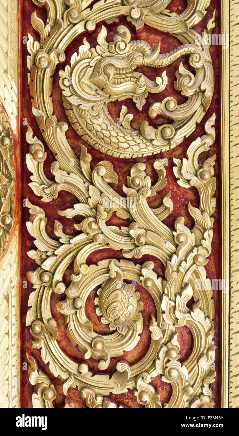 Patrón Oro tallado en la puerta delantera del público templo tailandés. Foto de stock