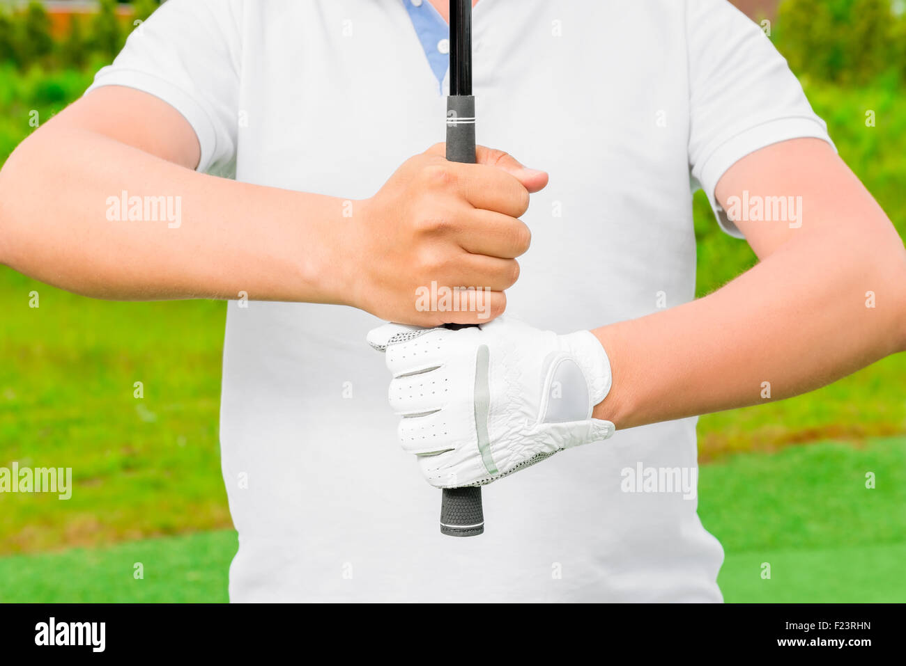 Las manos del hombre sostenga el putter firmemente sobre el campo de golf Foto de stock