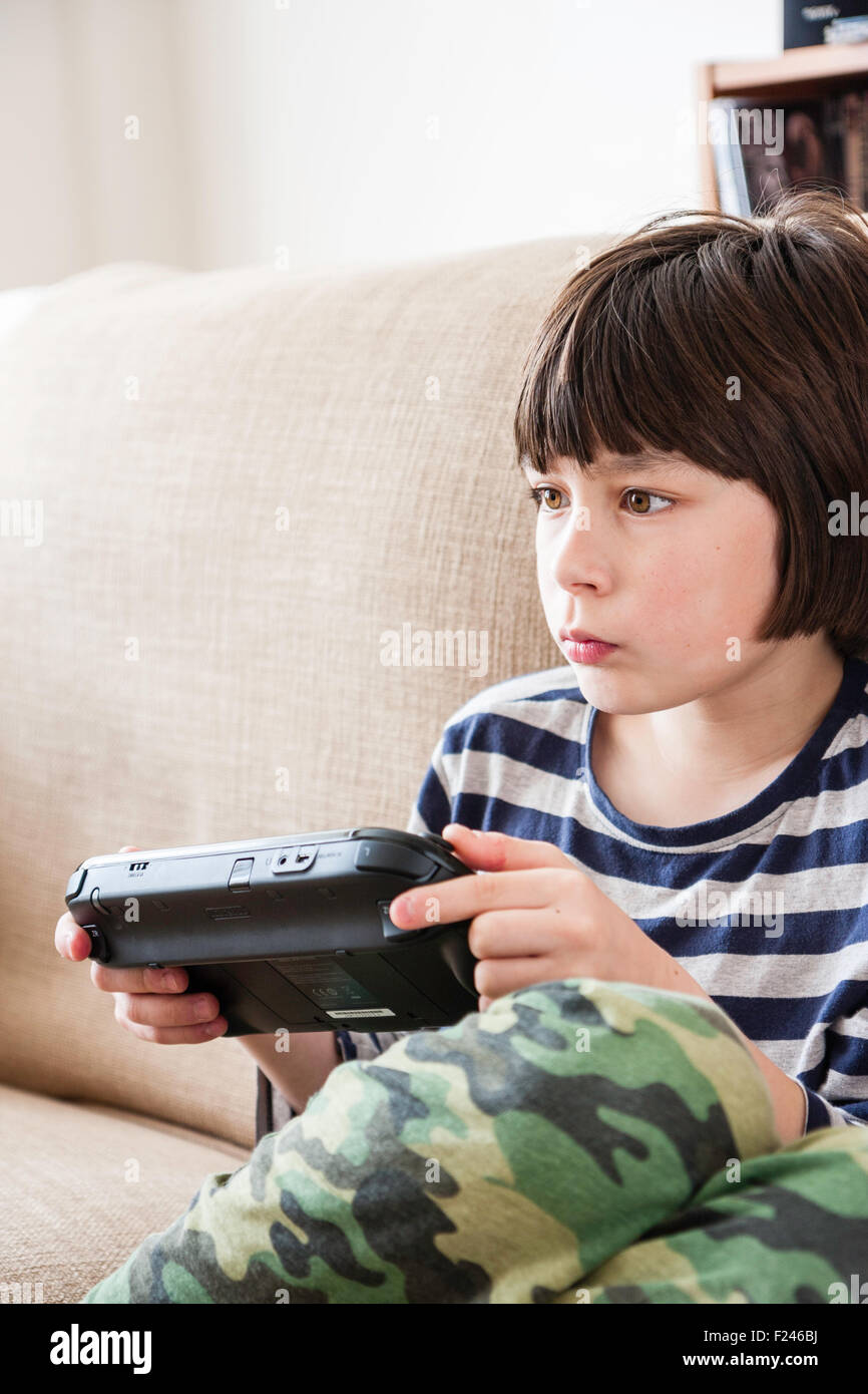 Ninos Caucasicos Masculinos El Muchacho De 10 A 12 Anos De Edad Sentada Sosteniendo Un Nintendo Wii Consola De Juegos En Ambas Manos Concentrando Vista Lateral De Cabeza Y Hombros Fotografia De