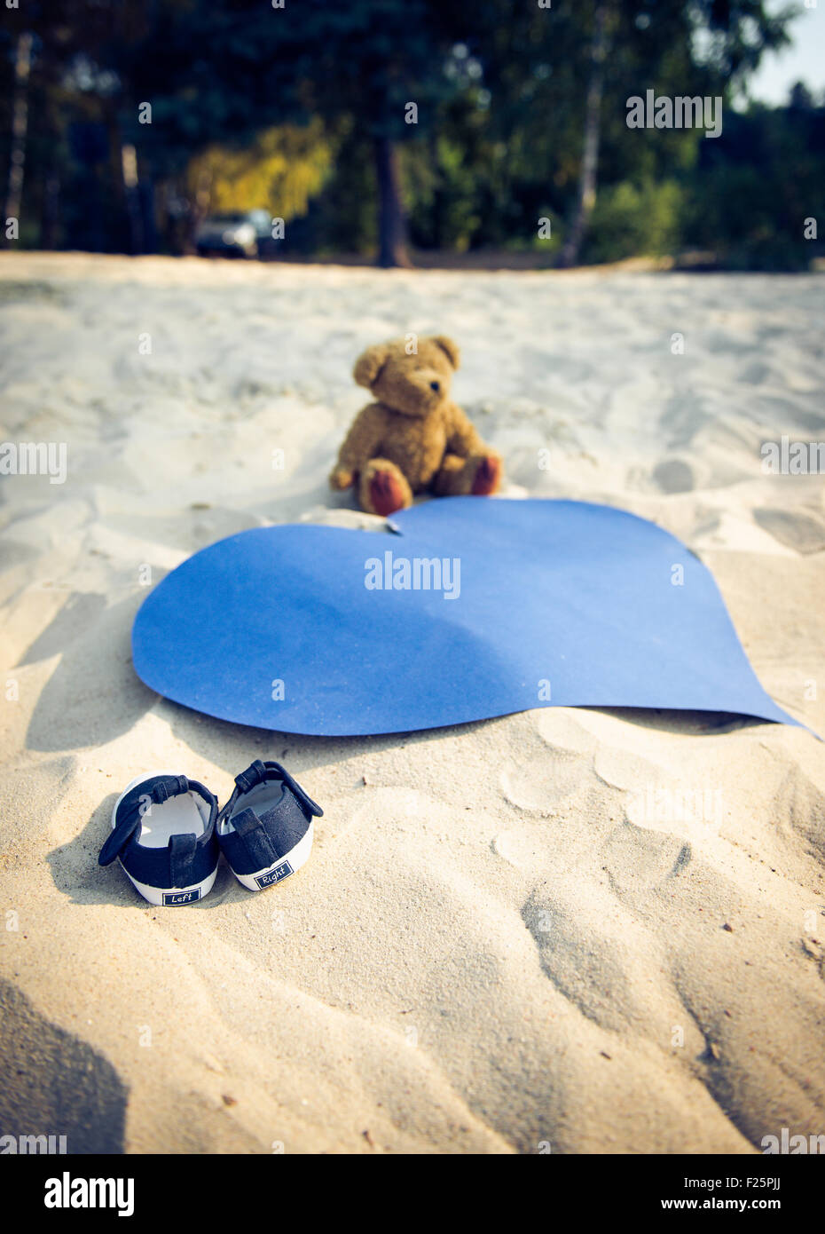 Foto de los diminutos zapatos, osito de peluche y un gran corazón azul en  una playa Fotografía de stock - Alamy