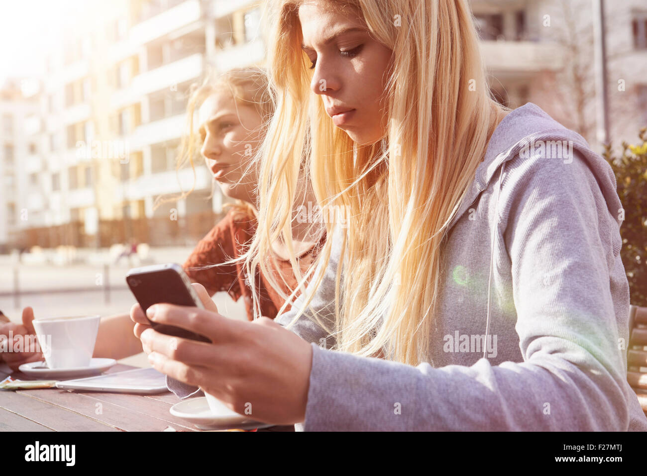 Adolescente mensajería de texto al café en la acera, Munich, Baviera, Alemania Foto de stock