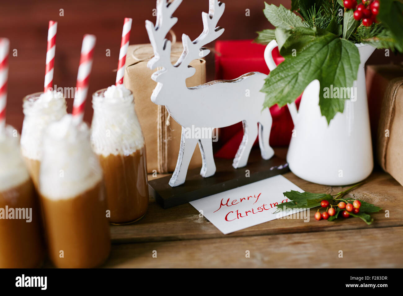 Venados de Madera, Porcelana jarrón con guelder hojas y bayas, botellas con chocolate caliente con crema batida y regalos en la mesa Foto de stock