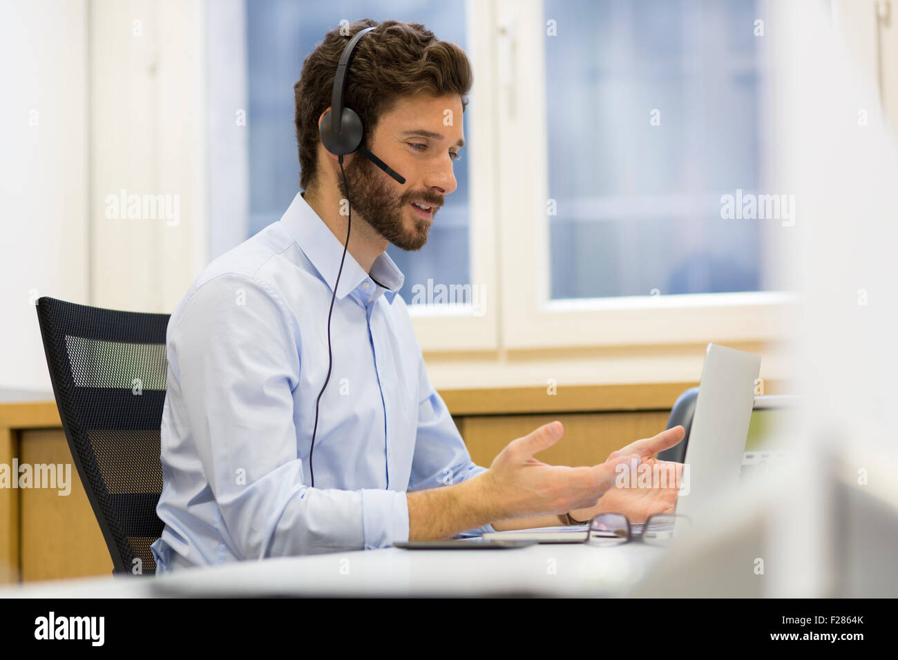 Hombre Barbado usando auriculares en videoconferencia Foto de stock