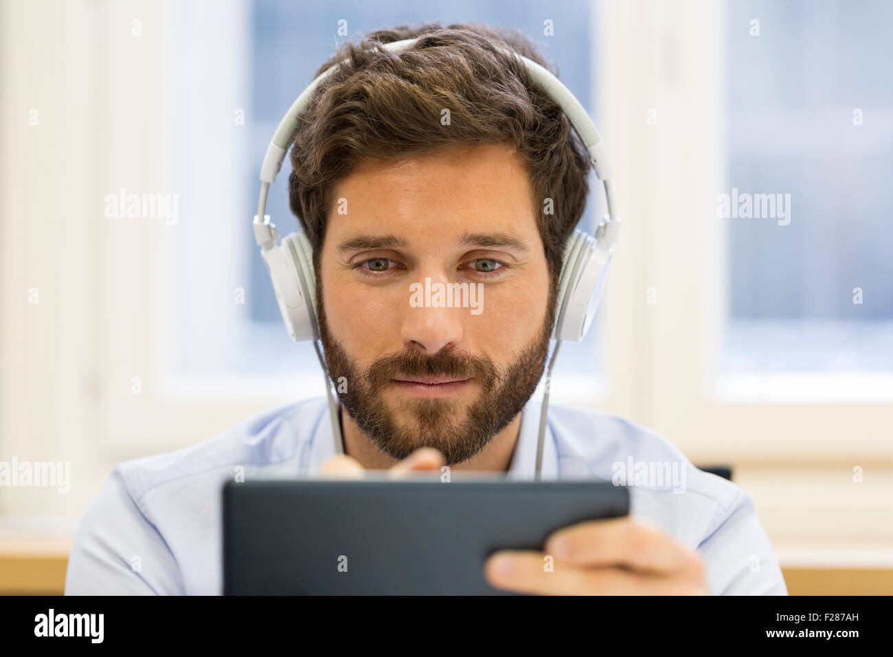 Retrato del empresario barbudo escuchando música en tablet pc Foto de stock