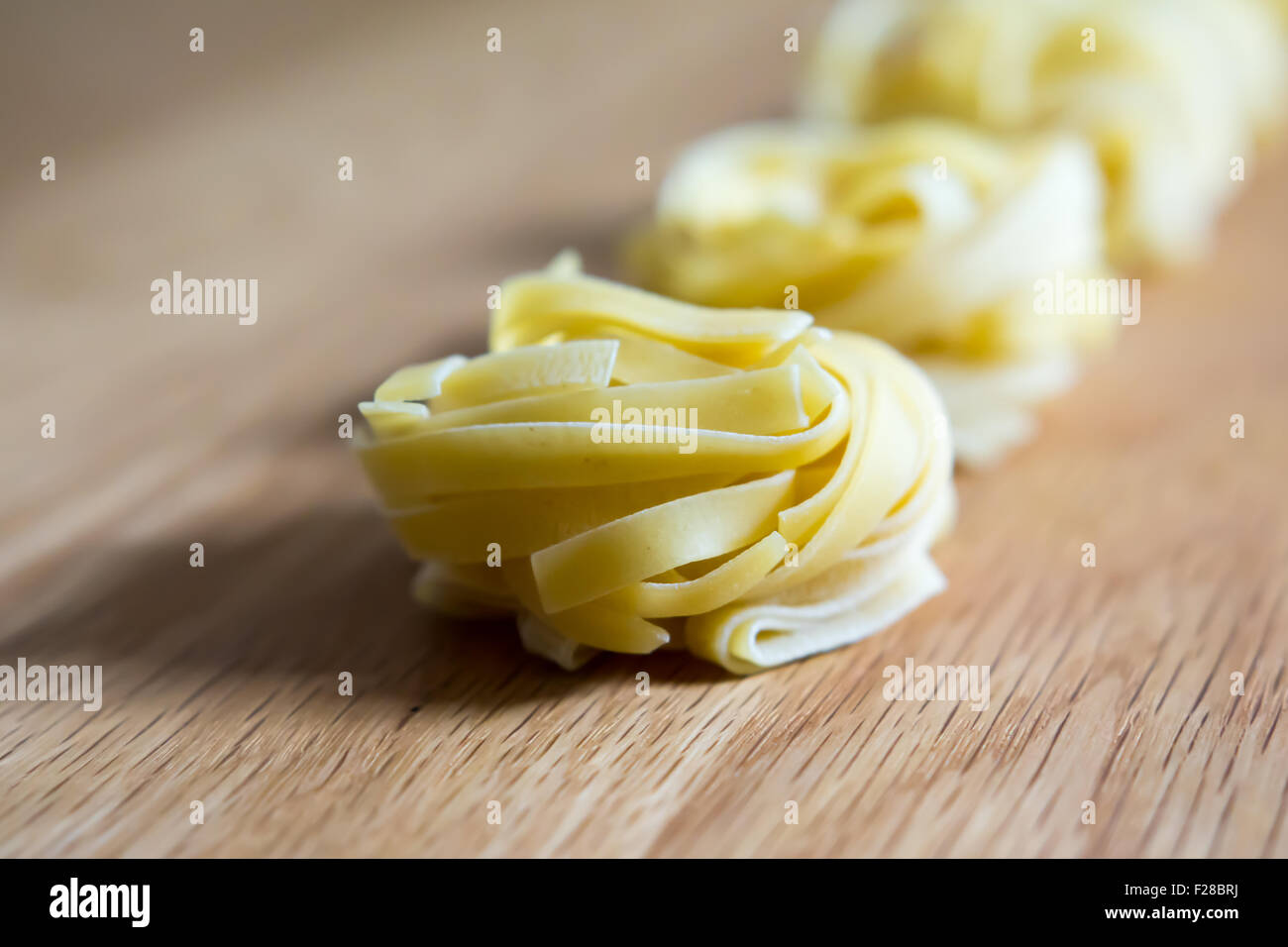 Materias tagliatelle poniendo en línea en placa de madera Foto de stock