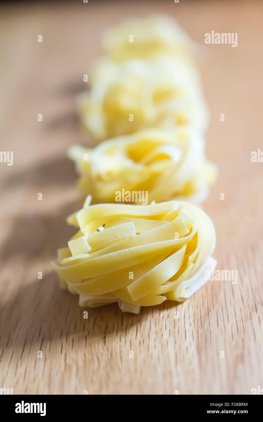 Materias tagliatelle poniendo en línea en placa de madera Foto de stock