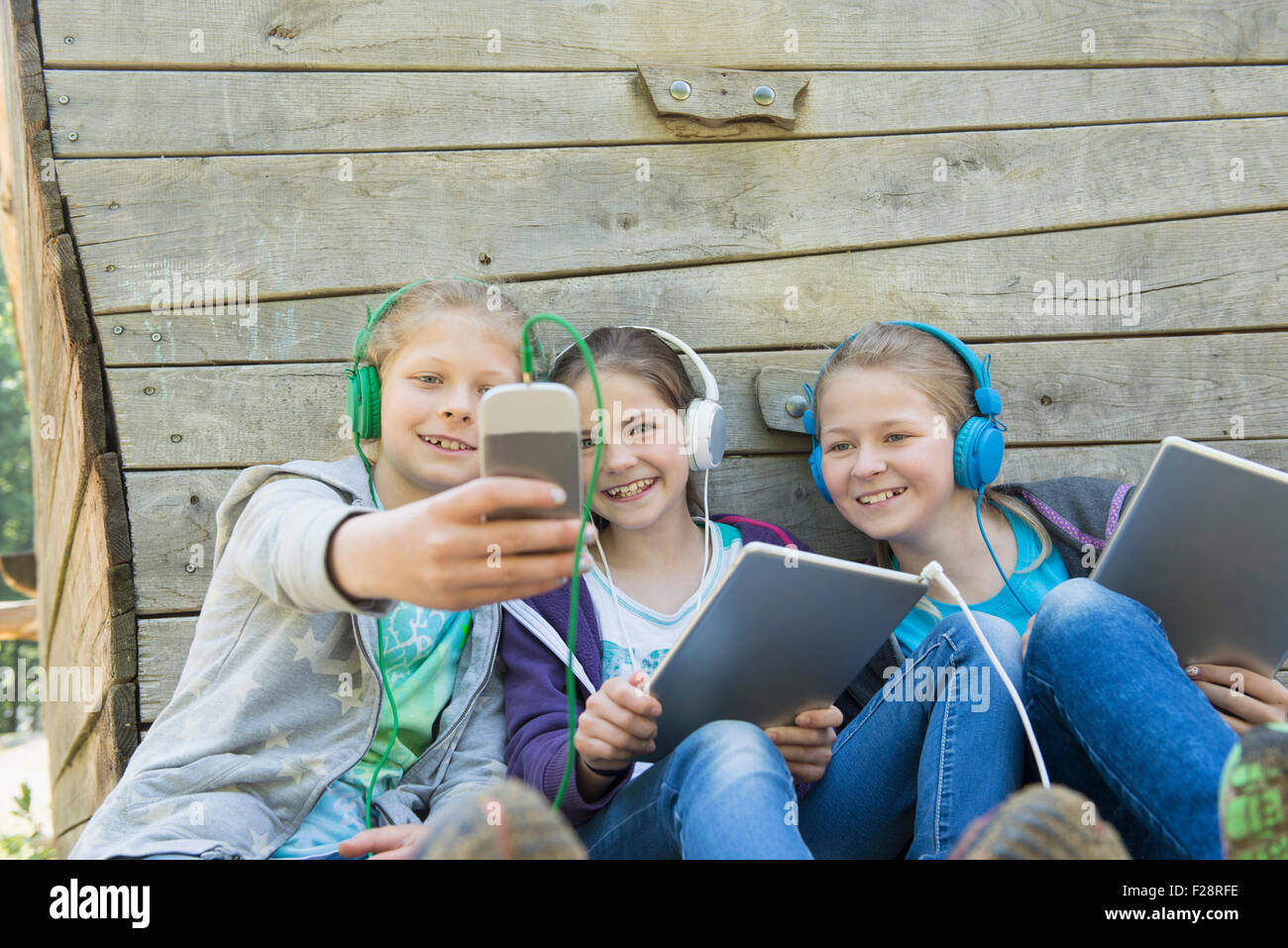 Tres amigos sentado en el patio de recreo y escuchando música, Munich, Baviera, Alemania Foto de stock