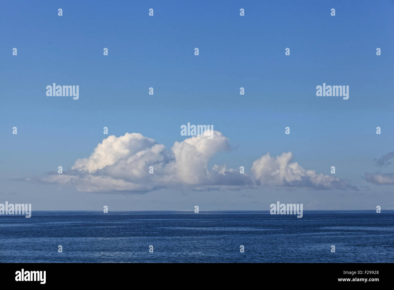 Una línea de esponjosas nubes en el horizonte se sitúa encima de un tranquilo océano Atlántico frente a la costa de Madeira. Foto de stock