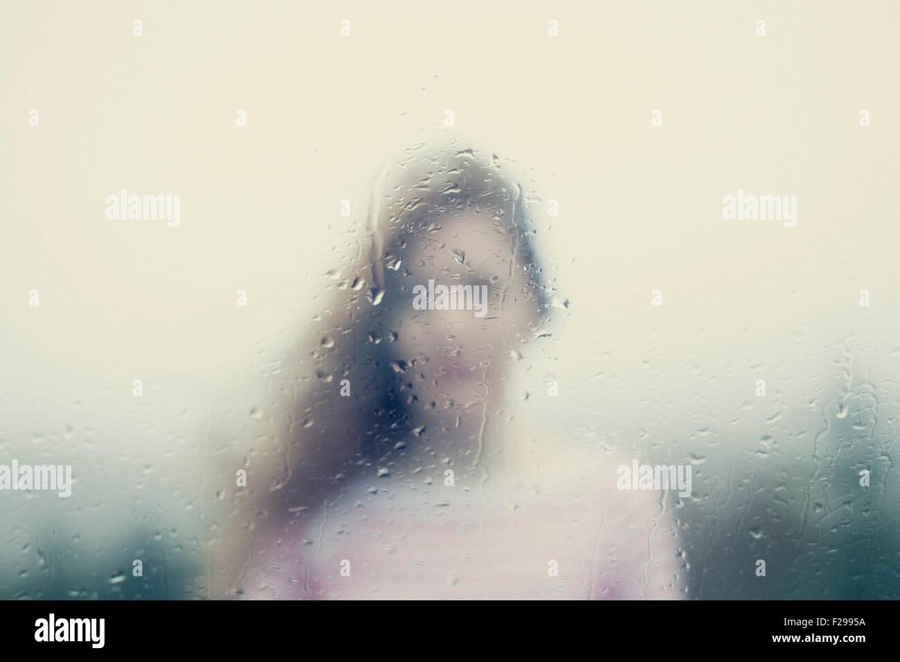 Imagen borrosa de una mujer a través de una ventana de lluvias Foto de stock