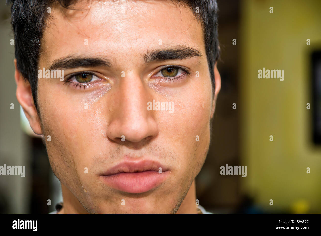 Cerca de un rostro pensativo guapo joven con lágrimas sobre su rostro, mirando a la cámara, preocupado o triste. Foto de stock