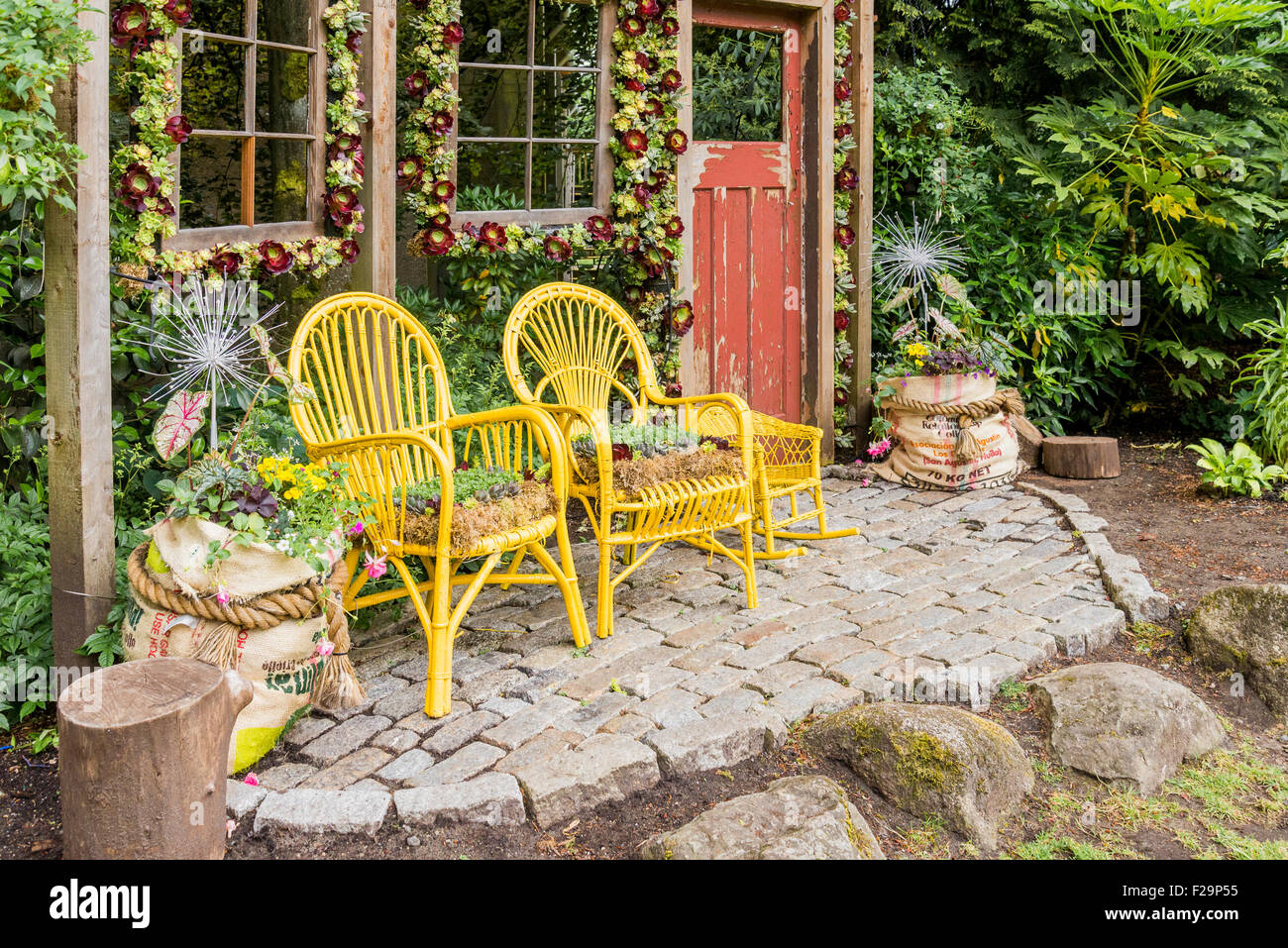 Pantalla de jardín con sillas de ratán como sembradoras Foto de stock