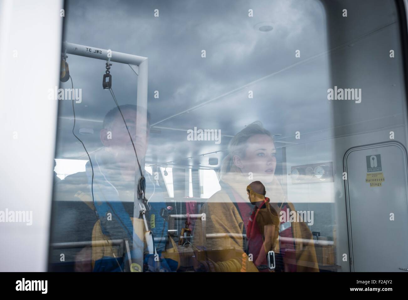 Capitán y investigadora reflejada en ventana en buque de investigación Foto de stock